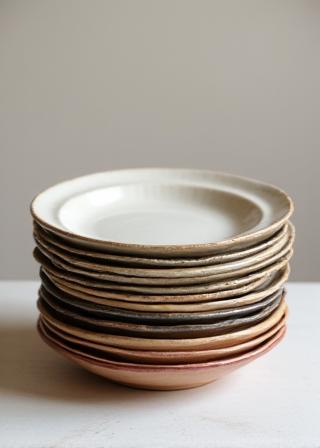 Pile d'assiettes artisanales aux glaçures variées.